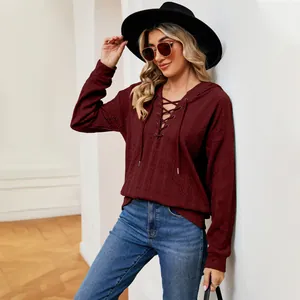 Detalle de estilo de una mujer con una sudadera con capucha granate con cordones y sombrero