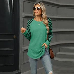 Detailed view of green crewneck top with striped raglan sleeves in a street setting