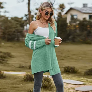 Model wearing a sage green knit cardigan with white sleeve stripes in a park setting