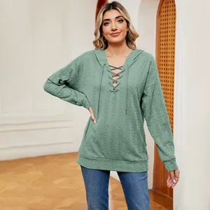 Detalle de sudadera con capucha verde salvia con escote de cordones y tejido texturizado