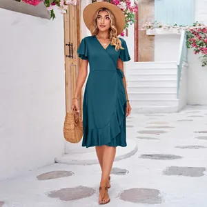 Elegant dark teal V-neck wrap dress with short ruffle sleeves in a Mediterranean scene
