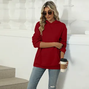 Stylish women's red hooded sweatshirt with pocket in an outdoor lifestyle setup.