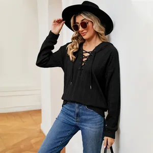 Detalle de sudadera negra con capucha, escote con cordones y tejido texturizado