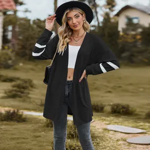 Outdoor full body shot of woman wearing a black and white striped long-sleeved knitted cardigan.