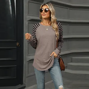 Outdoor fashion shot of a color-block long sleeve tee with striped sleeves and curved hem.