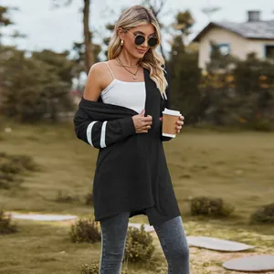 Stylish black knit cardigan with white sleeve stripes worn by a model in an outdoor setting.