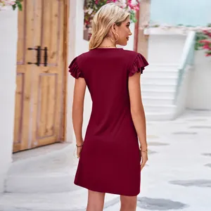 Rear view of a stylish wine red summer dress with flutter sleeves in a sunny alleyway.