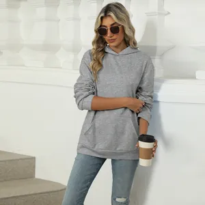 Close-up detail of a grey oversized hooded sweatshirt worn by a model in casual setting