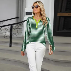 Full body street style shot of the women's green striped V-neck long sleeve shirt