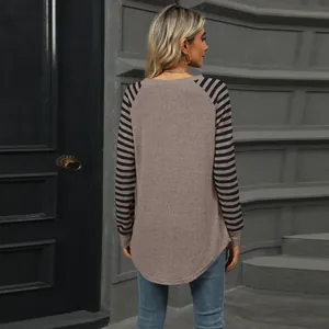 Back view of a chic women's long sleeve top featuring striped sleeves and curved hem