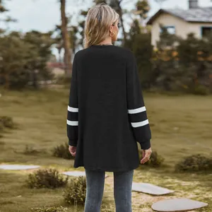 Rear view of a stylish black long-sleeved cardigan with white sleeve stripes outdoors