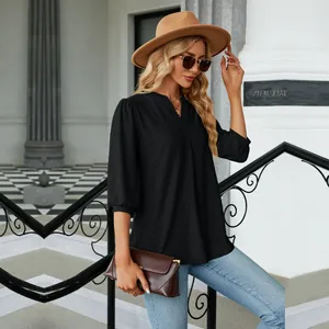 Primer plano de una elegante blusa negra de jacquard con cuello en V y mangas 3/4 al aire libre