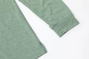 Detailopname van de lichtgroene mouwmanchet en zijsplitzoom op een getextureerde stof.