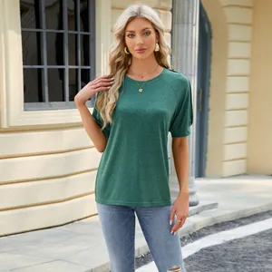 Full view of a green raglan sleeve T-shirt on a model in a sunny outdoor street setting