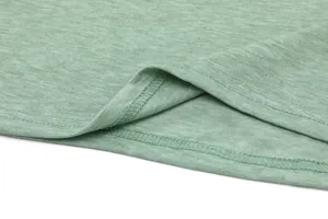 Detailopname van groene gemêleerde stof en dubbelgestikte zoom van casual t-shirt
