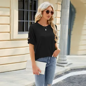 Chic woman wearing a black raglan sleeve t-shirt with gold shoulder button accents outdoors