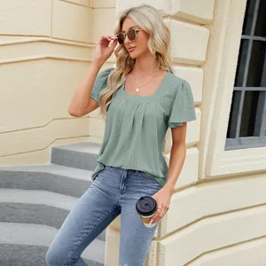 Elegant sage green eyelet t-shirt featuring a square neck and pleated details on model outdoors.