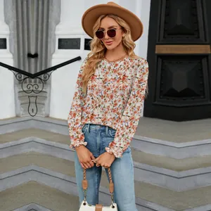 Close-up detail of long-sleeve floral print blouse with round neck and ruffled cuffs