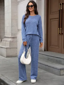 Full view of women's blue crewneck knitted loungewear set in outdoor architectural setting.