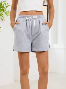 Detailed view of gray athletic shorts featuring white drawstrings and side stripes.