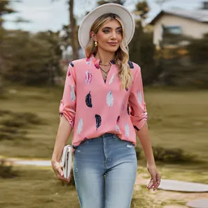 Woman wearing a stylish pink V-neck blouse with feather patterns in a garden