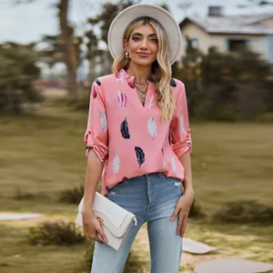 Detail view of a loose pink V-neck blouse with colorful feather print and 3/4 sleeves