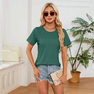 Lifestyle shot of a woman wearing a dark green smocked crewneck T-shirt and denim shorts