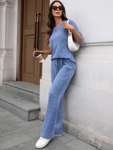 Model wearing a blue ribbed knit lounge set with long sleeve top and wide-leg trousers.