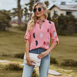 Detail view of pink V-neck shirt featuring elegant feather print and rolled sleeves