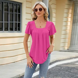 Outdoor street view of a blonde model wearing a pink square neck eyelet jacquard top