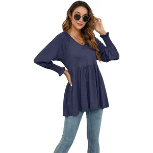 Dettaglio della tunica blu navy con scollo a V, polsini arricciati e orlo a peplo per donna