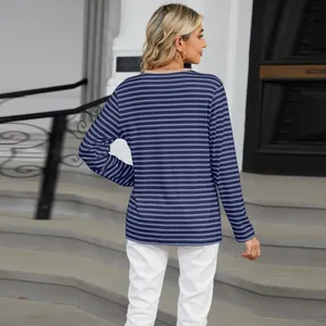 Back view of a casual blue striped long sleeve T-shirt worn by a blonde model outdoors