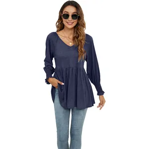 Vista dettagliata del top blu navy con scollo a V, vita a peplo e polsini a pieghe