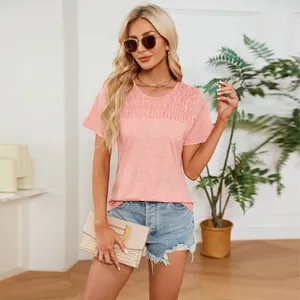 Close-up of woman wearing pink smocked t-shirt with denim shorts in indoor setting