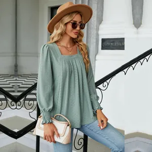 Detail view of sage green square-neck blouse with jacquard texture and smocked cuffs
