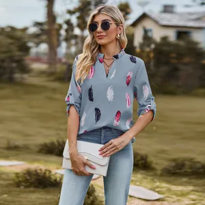 Outdoor lifestyle photo of a woman in a light blue V-neck feather print blouse with 3/4 sleeves