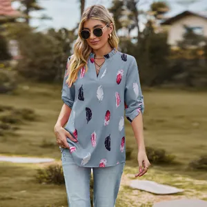 Detail of women's V-neck feather print shirt with roll-tab sleeves in outdoor setting