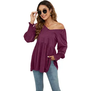 Vista completa di un elegante top bordeaux a maniche lunghe con scollo a V e vita a balze