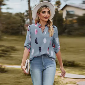 Detail of stylish blue V-neck blouse featuring vibrant feather print and loose fit.