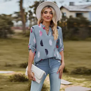 Woman wearing a stylish V-neck feather print loose shirt in a scenic outdoor setting