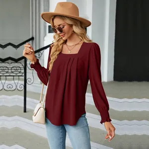Detailed shot of the burgundy jacquard blouse featuring pleated square neck and smocked cuffs