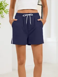 Close-up detail of navy blue sporty shorts featuring white drawstrings and side stripes