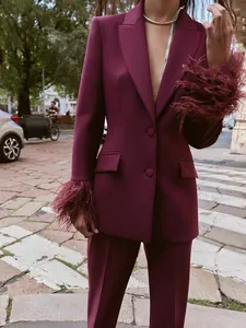 Nahaufnahme eines weinroten Blazer-Sets mit luxuriösen Federbesatz-Manschetten im Stadtbild