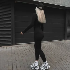 Vista posteriore di una modella che indossa una sexy tuta intera nera aderente a maniche lunghe
