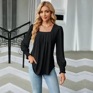 Outdoor full shot of a woman wearing a black square neck jacquard blouse with pleats