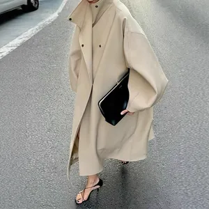 Elegant beige long trench coat with stand collar and batwing sleeves in urban street setting.