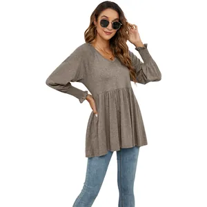 Modella che indossa un top peplum marrone con scollo a V e eleganti polsini smock