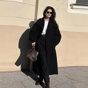 Elegant long black batwing sleeve coat worn by a model in a stylish outdoor setting.