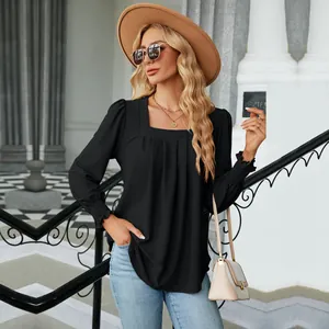 Detail view of a woman wearing a black square neck jacquard blouse in an outdoor setting