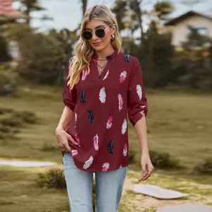 Detailed view of women's burgundy blouse with vibrant feather print and V-neckline